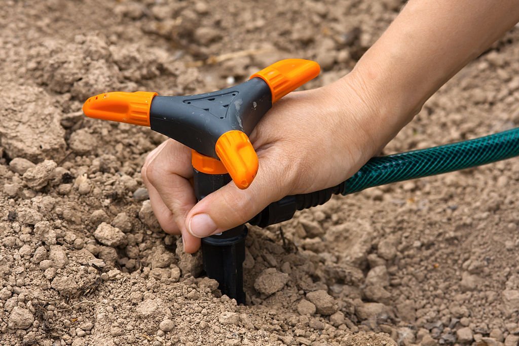 hand installing sprinkler for garden irrigation, closeup